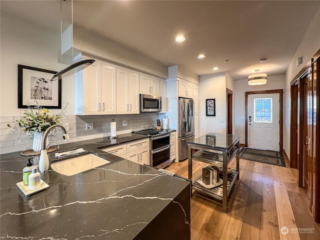 kitchen with hardwood / wood-style floors, stainless steel appliances, decorative backsplash, white cabinets, and sink