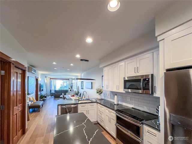 kitchen with white cabinetry, stainless steel appliances, decorative backsplash, light hardwood / wood-style floors, and a wall mounted AC