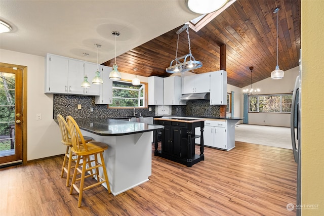 kitchen featuring white cabinetry, wood ceiling, decorative light fixtures, a center island, and vaulted ceiling