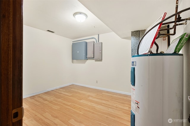 basement featuring wood-type flooring, electric water heater, and electric panel