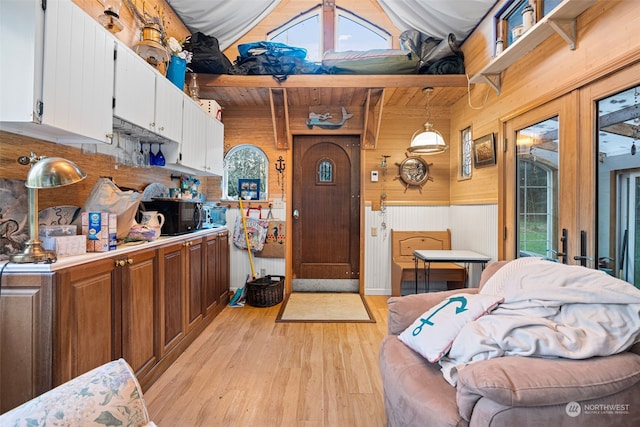 kitchen featuring wood ceiling, white cabinets, decorative light fixtures, light wood-type flooring, and wood walls