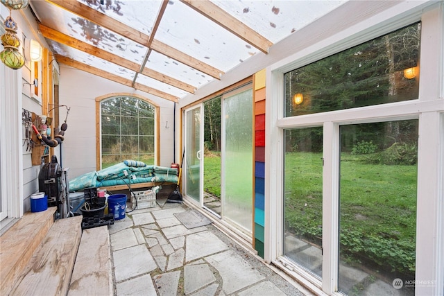 sunroom / solarium featuring lofted ceiling with beams