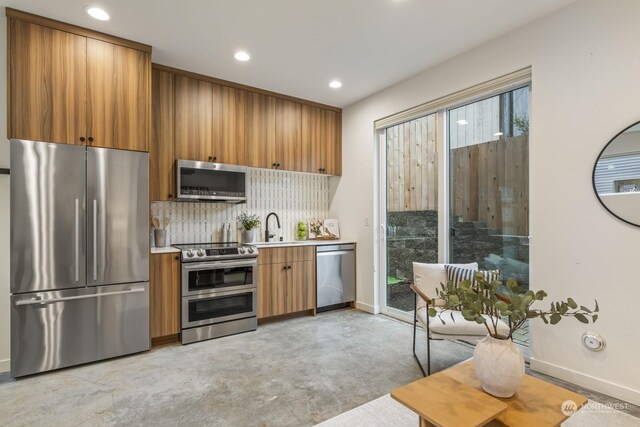 kitchen with a sink, light countertops, appliances with stainless steel finishes, brown cabinets, and backsplash