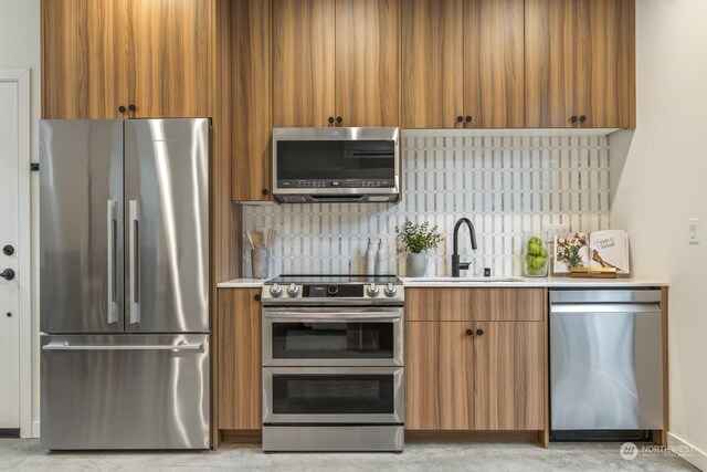 kitchen featuring decorative backsplash, stainless steel appliances, light countertops, and a sink