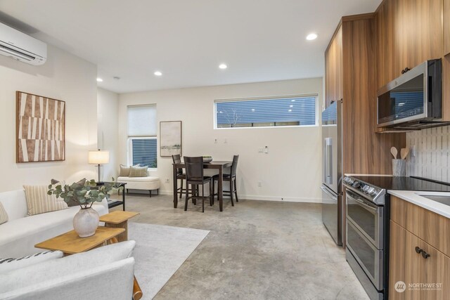 kitchen featuring a wall mounted air conditioner, brown cabinets, recessed lighting, concrete floors, and appliances with stainless steel finishes