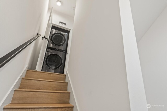 staircase featuring visible vents and stacked washer / dryer