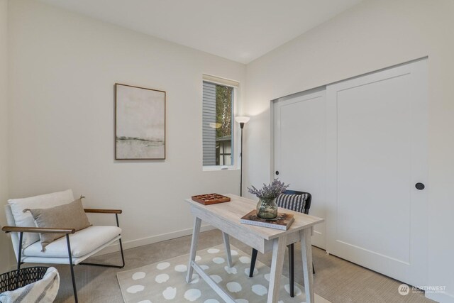 office space with baseboards and light carpet