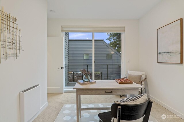 home office with heating unit, light colored carpet, and baseboards