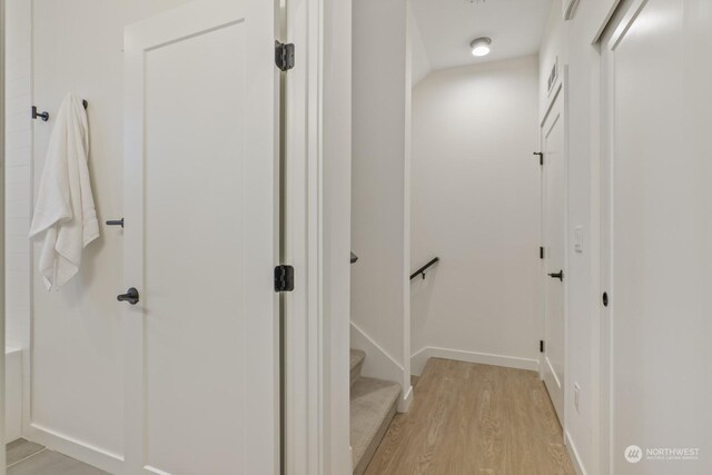 corridor with light wood-style floors and baseboards