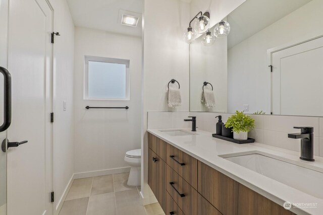 bathroom featuring tile patterned flooring, toilet, backsplash, and a sink