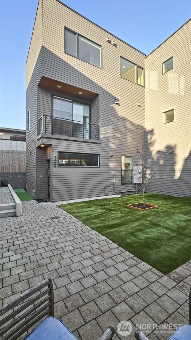 rear view of property featuring a patio area, a lawn, a balcony, and fence