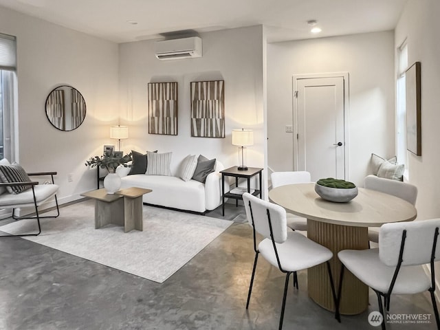 living area featuring a healthy amount of sunlight, concrete floors, and a wall mounted AC