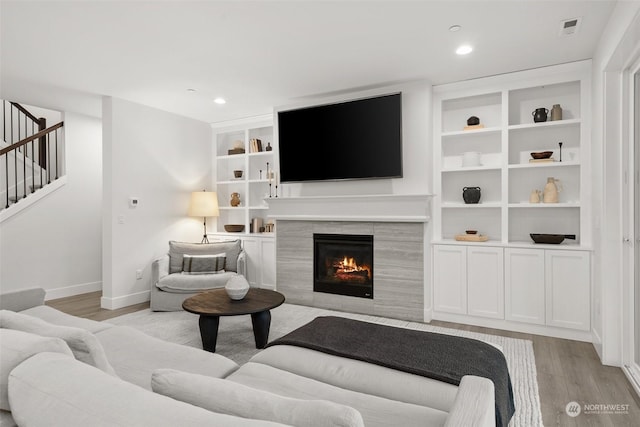 living room with light hardwood / wood-style floors and a tiled fireplace