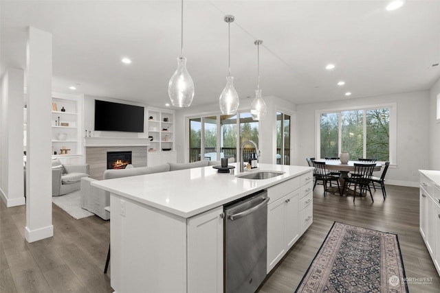 kitchen featuring pendant lighting, a kitchen island with sink, white cabinets, sink, and stainless steel dishwasher