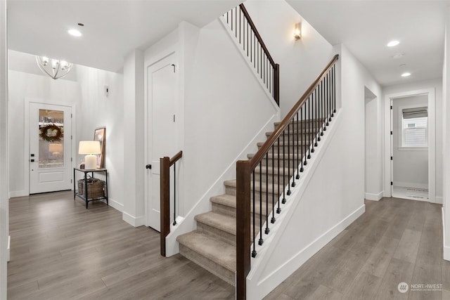 staircase with hardwood / wood-style flooring and a notable chandelier