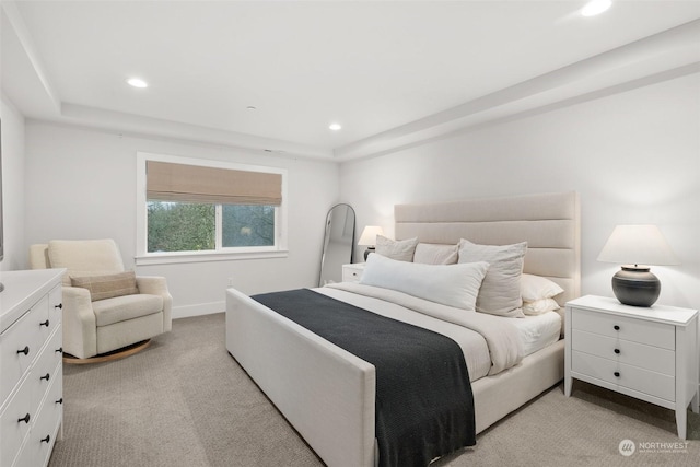 bedroom featuring light colored carpet and a tray ceiling