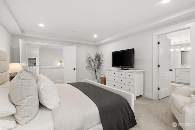 carpeted bedroom with ensuite bathroom and a tray ceiling