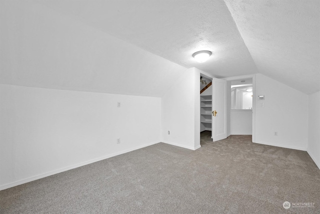 bonus room featuring carpet, lofted ceiling, and a textured ceiling