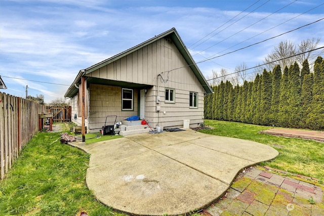 rear view of house featuring a lawn and a patio