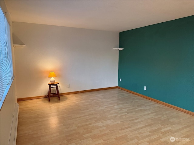 empty room featuring light wood-type flooring and a baseboard heating unit