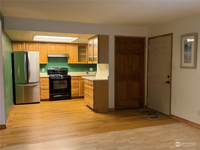 kitchen with light hardwood / wood-style floors, stainless steel refrigerator, and black electric range