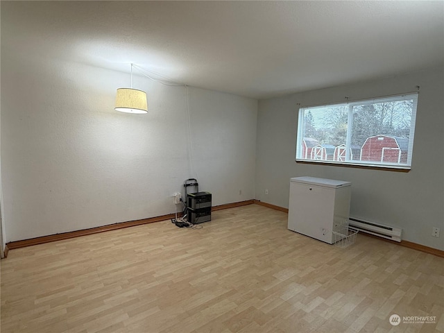 spare room featuring a baseboard radiator and light hardwood / wood-style flooring