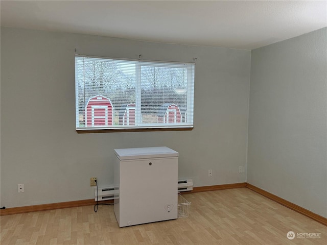 empty room with a baseboard radiator and light hardwood / wood-style flooring