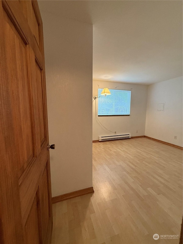 empty room featuring baseboard heating and light hardwood / wood-style floors