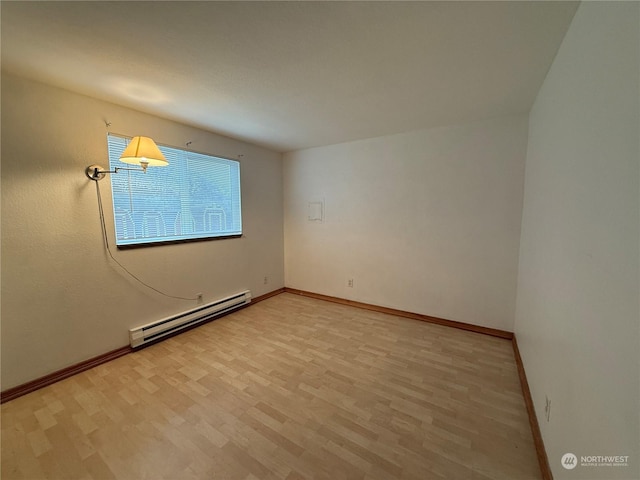 unfurnished room featuring light wood-type flooring and a baseboard heating unit