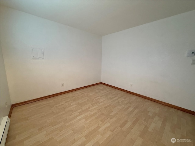 unfurnished room featuring baseboard heating and light hardwood / wood-style flooring