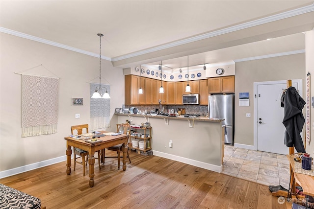 kitchen with stainless steel appliances, backsplash, kitchen peninsula, pendant lighting, and a breakfast bar