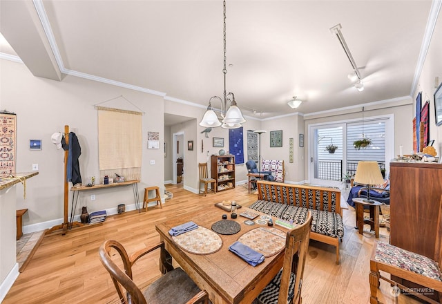 dining room with light hardwood / wood-style floors, crown molding, rail lighting, and a chandelier