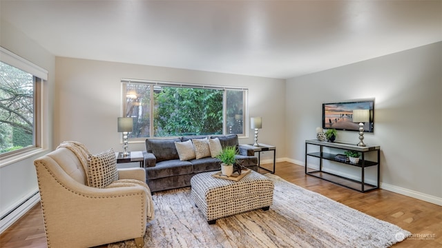 living room featuring hardwood / wood-style flooring, plenty of natural light, and a baseboard heating unit