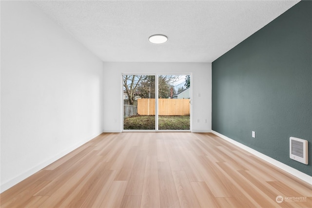 spare room featuring a textured ceiling and light hardwood / wood-style flooring