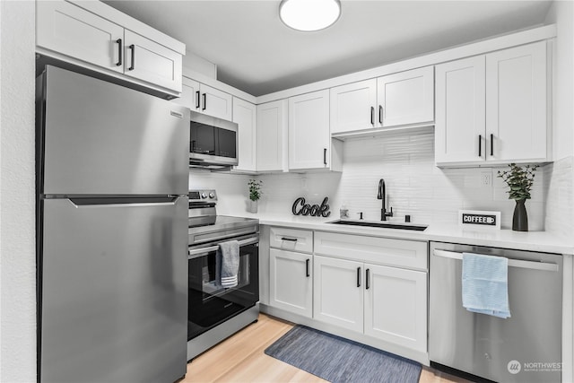 kitchen featuring appliances with stainless steel finishes, tasteful backsplash, white cabinetry, and sink