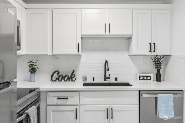 kitchen with stainless steel appliances, white cabinets, sink, and backsplash