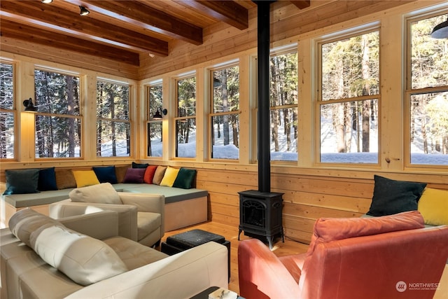 sunroom with beam ceiling and a wood stove