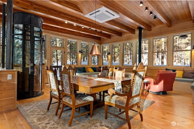 dining space featuring rail lighting, light hardwood / wood-style flooring, wooden walls, and wood ceiling