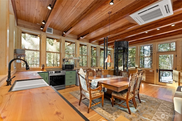 dining room featuring sink, light hardwood / wood-style flooring, beamed ceiling, wooden walls, and wood ceiling