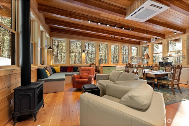 sunroom / solarium featuring beamed ceiling, a wood stove, and wood ceiling