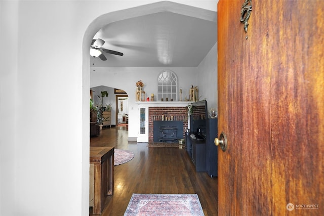 living room with dark hardwood / wood-style flooring, a brick fireplace, and ceiling fan