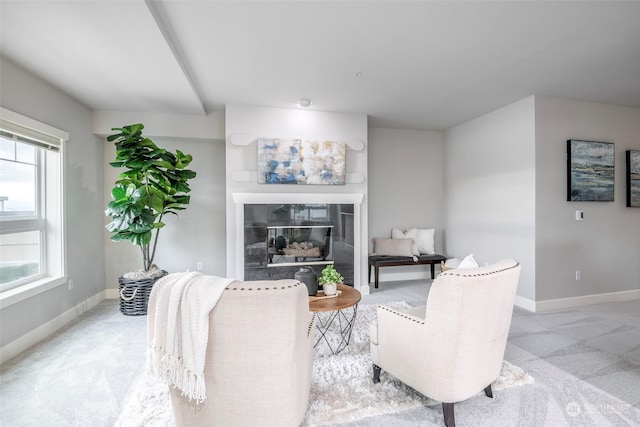 living room featuring a tile fireplace, a healthy amount of sunlight, and light colored carpet