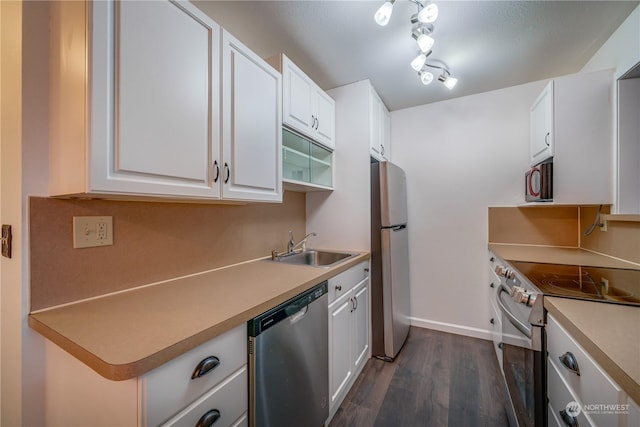 kitchen with sink, white cabinets, dark wood-type flooring, and appliances with stainless steel finishes