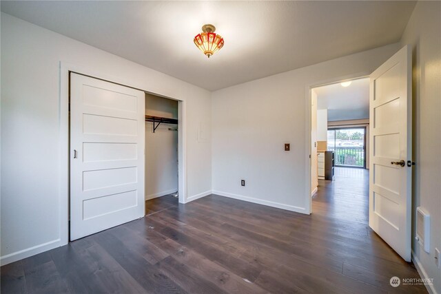 unfurnished bedroom with a closet and dark wood-type flooring