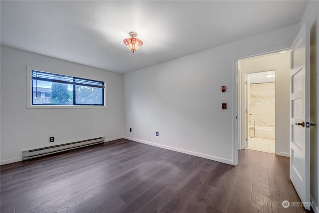 empty room with baseboard heating and dark wood-type flooring