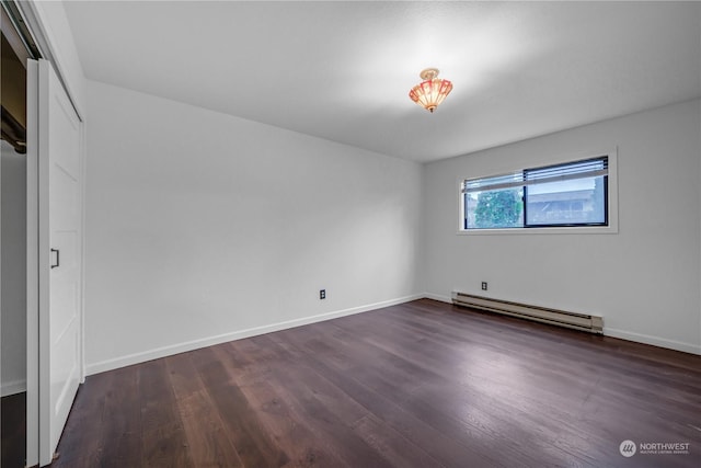 spare room with a baseboard radiator and dark wood-type flooring