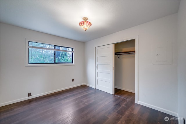 unfurnished bedroom with electric panel, a closet, and dark hardwood / wood-style floors