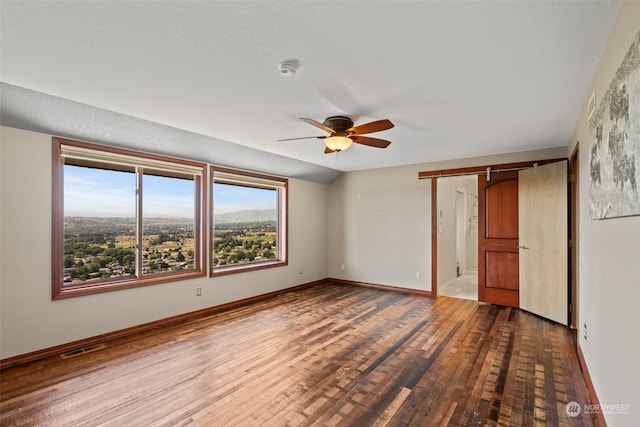 unfurnished bedroom featuring hardwood / wood-style floors, a barn door, ceiling fan, and lofted ceiling