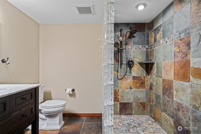 bathroom featuring tiled shower, vanity, and toilet