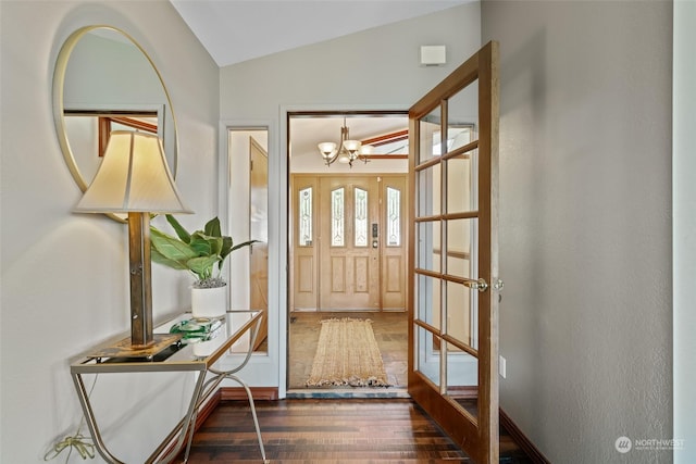 foyer entrance featuring dark hardwood / wood-style flooring, french doors, lofted ceiling, and a notable chandelier